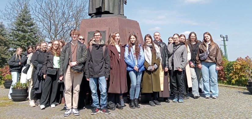 Uczestnicy wycieczki na wspólnym zdjęciu pod pomnikiem Jana Pawła II.