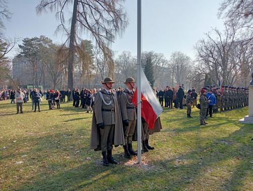 Żołnierze stojący obok masztu na który zostanie za chwilę wciągnięta flaga Polski